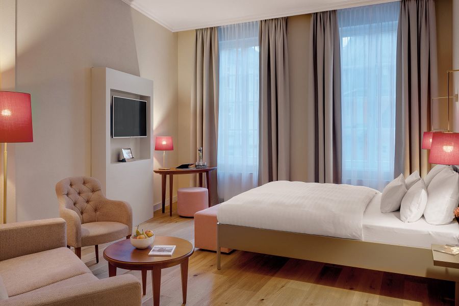 gemütliches Hotelzimmer mit Sessel und verschiedenen Lampen in rot